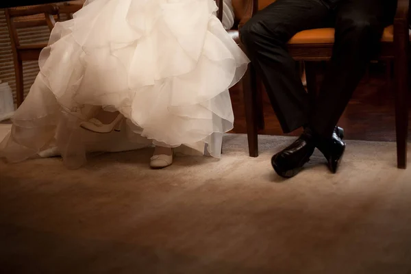 Bein und Schuhe des Hochzeitspaares auf Stuhl im Innenraum — Stockfoto