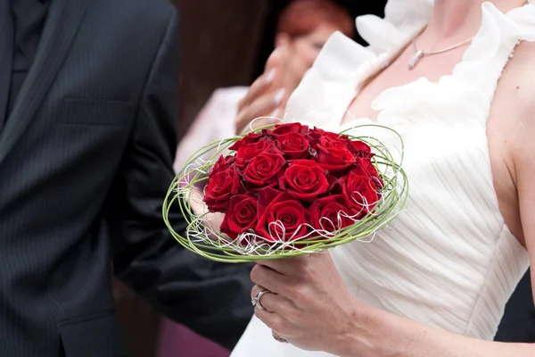 Unrecognizable bride and groom with wedding bouquet of red roses — Stock Photo, Image