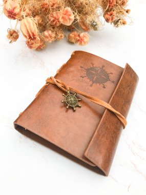 Kurumuş çiçekler ve deri bir defter.
