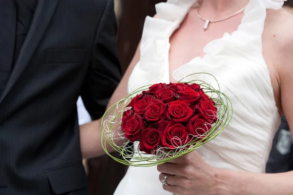 Unrecognizable bride and groom with wedding bouquet of red roses — Stock Photo, Image
