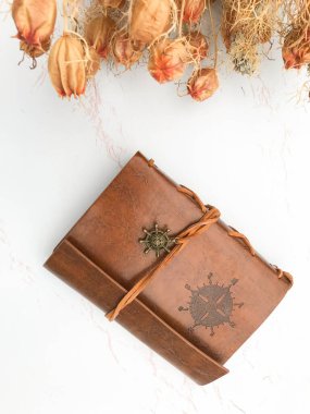 Kurumuş çiçekler ve deri bir defter.