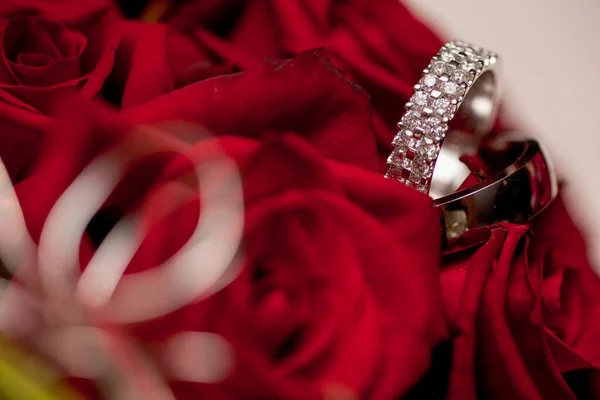 Anéis de casamento em rosas vermelhas fundo — Fotografia de Stock