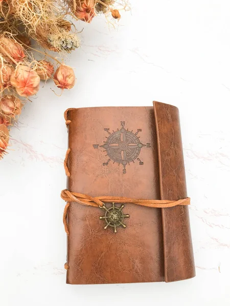 Kurumuş çiçekler ve deri bir defter.