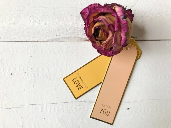 Aşk, hediye etiketleri ve kurumuş bir gül.