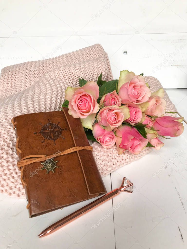 Pink roses and a leather notebook on a pink blanket