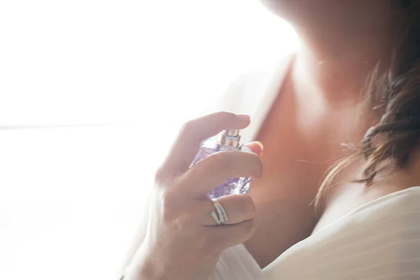 Cropped image of beautiful young woman using perfume against a white background — Stock Photo, Image