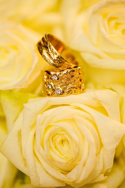 Обручальные кольца на фоне белых роз — стоковое фото