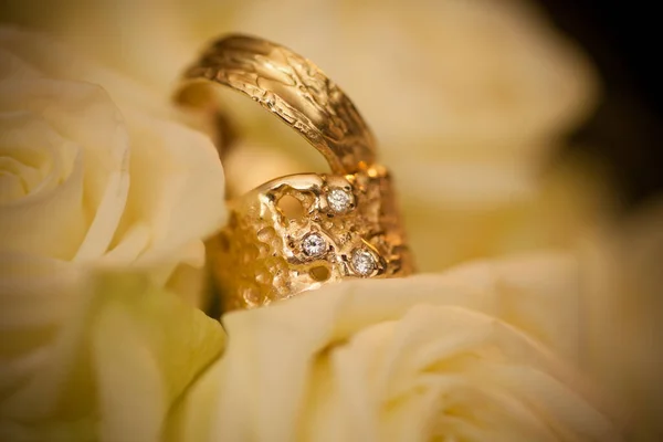 Обручальные кольца на фоне белых роз — стоковое фото