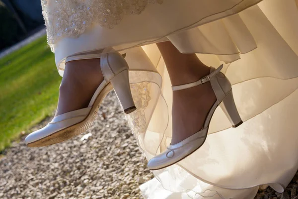 Невеста сидит на стуле снаружи, у ног невесты дизайнерские туфли на высоких каблуках — стоковое фото