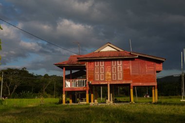 Alor Star, Kedah Malezya 'da geleneksel Malezya evi ve günbatımı ile birlikte dağın arka planında güzel bir pirinç tarlası