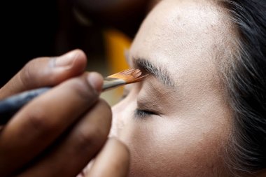 Kadın yüzüne makyaj fırçası sürüyor.