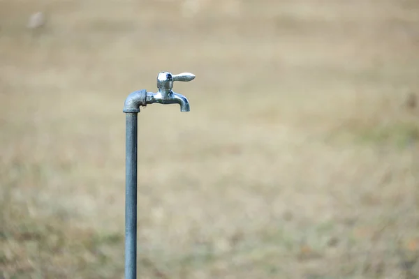 close up faucet water at park  at dry grassland