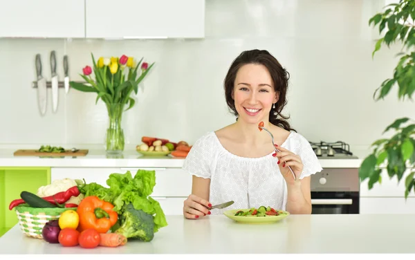 Mulher comendo salada na cozinha — Fotografia de Stock
