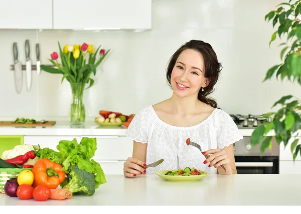 Mujer comiendo ensalada en la cocina —  Fotos de Stock