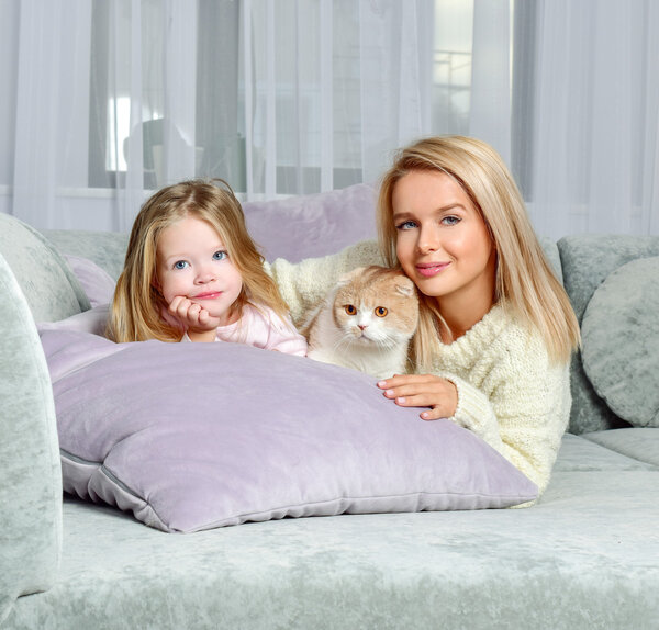 Mother and daughter at home with cat. 