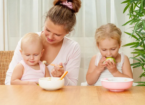 Mãe alimentando suas duas filhas — Fotografia de Stock