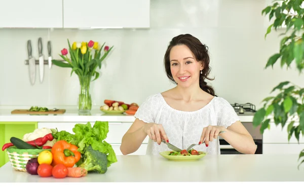 Frau isst Salat in Küche. — Stockfoto
