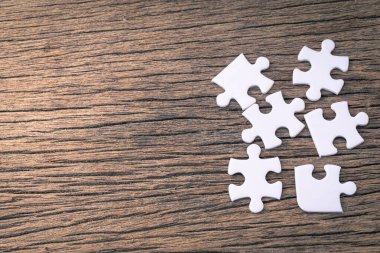 Tahta bir arka planda beyaz yapboz parçaları var.