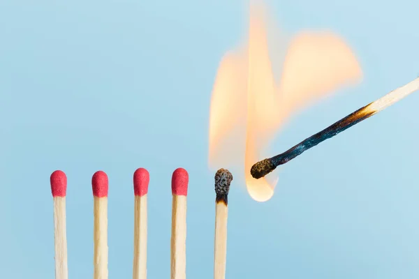 Matches in group burning safety-match with red, orange, yellow fire. Isolated on blue sky background detail object art