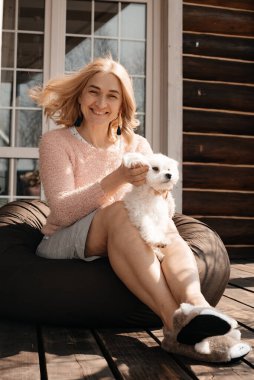 Verandada oturan köpekli çekici bir kadın.
