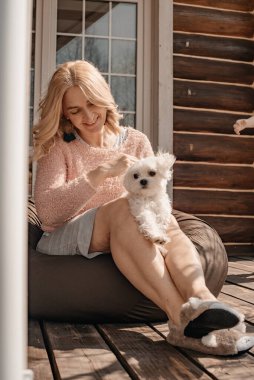 Verandada oturan köpekli çekici bir kadın.