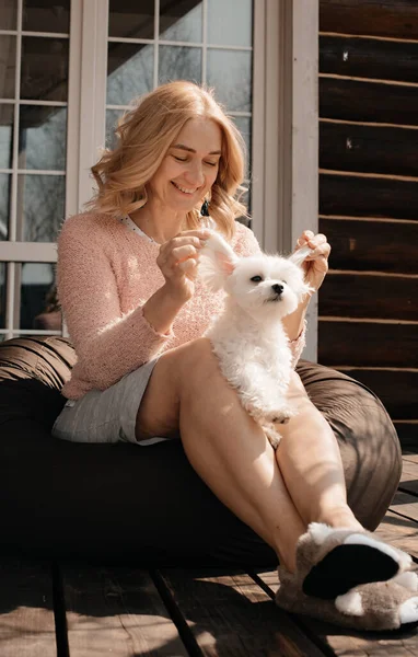 Verandada oturan köpekli çekici bir kadın.