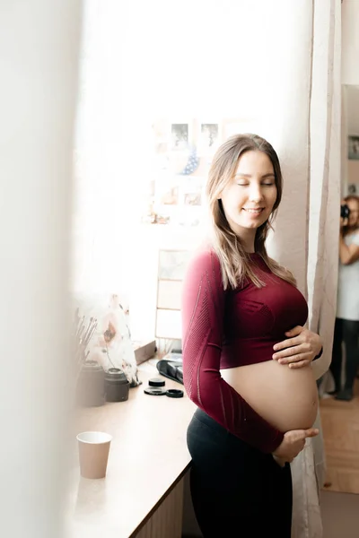 Gravid Kvinde Drikker Ved Vinduet Hun Bærer Stramme Sport Kostume - Stock-foto