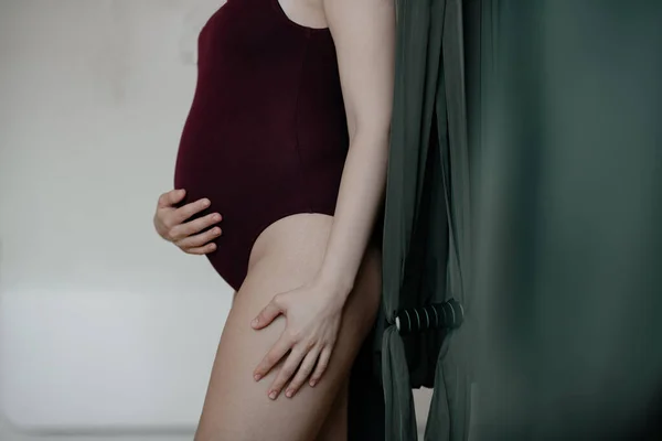 妊婦さんがスタジオでヨガをしています 彼女はきつい体をしている 彼女は彼女の腹を抱擁し 将来の赤ちゃんに非常に注意しています 母のケア 若い母親 女性と子供 健康的な生活 フィットネスの概念 — ストック写真