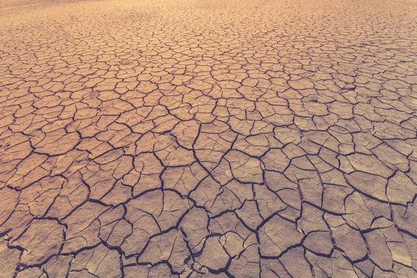 La tierra está cubierta de grietas como símbolo de sequía, condiciones climáticas extremas o como fondo. Imagen tonificada —  Fotos de Stock