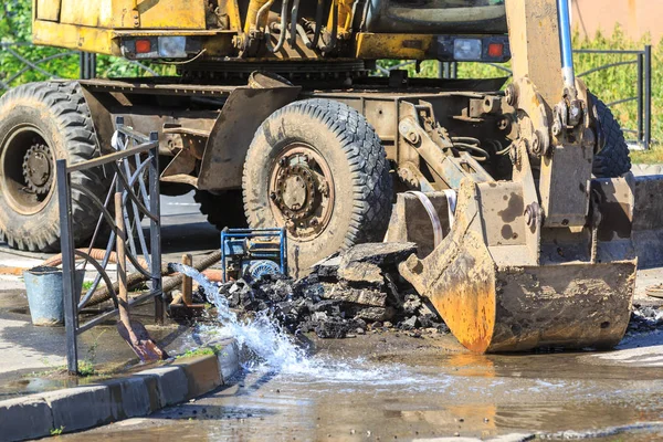 Excavator helps to eliminate the problem of breaking a pipe in the street on a hot summer day — Stock Photo, Image