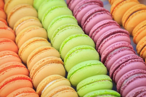 Una gran cantidad de galletas redondas con sabores de melocotón, avellanas sabores, pistachos sabores, frambuesas sabores se apilan en una fila en la caja — Foto de Stock