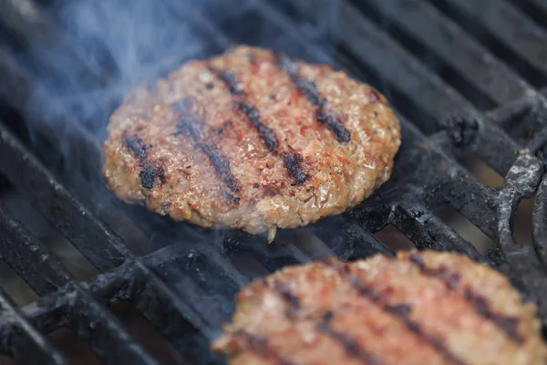 Hambúrgueres de carne de vaca apetitosos estão assando na churrasqueira — Fotografia de Stock