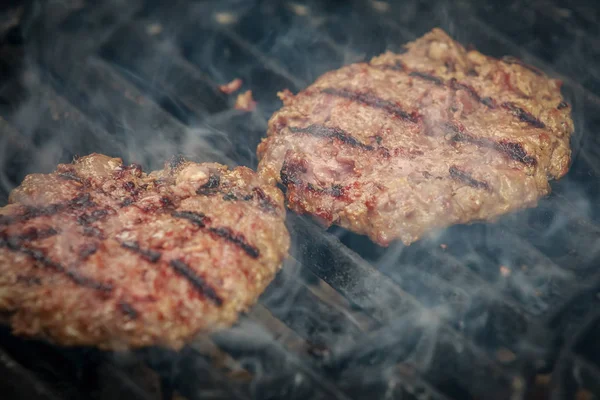 Zamatos és étvágygerjesztő marha hamburgerek pörkölés a Bbq grill-füst — Stock Fotó
