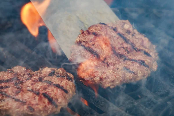 Hambúrgueres de carne de vaca apetitosos estão assando na grelha — Fotografia de Stock