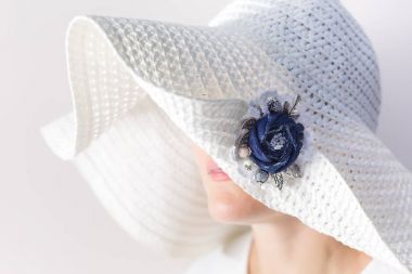 Denim el yapımı yapılan bir broş ile beyaz şapkalı gizemli bir kadın portresi
