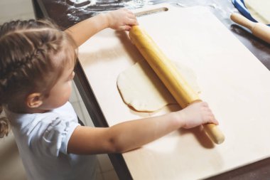 Küçük kız büyük bir oklava ile hamur dışarı rulo