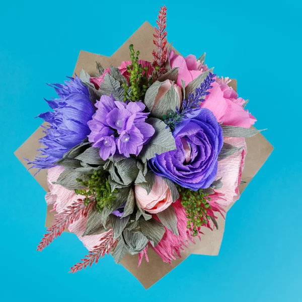 Artificial flowers handmade as decoration of a greeting card on a turquoise color background