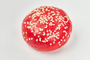 Yuvarlak lezzetli kırmızı çörekler beyaz arka planda susam tohumları serpiştirilmiş.