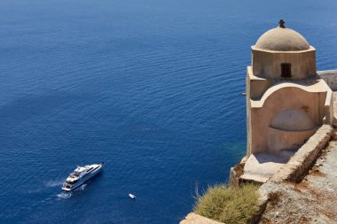 Oia, Santorini, Yunanistan, 21 Ağustos 2013: Mavi denizde seyreden küçük bir kilise ve lüks bir yat manzarası
