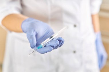 Doktor avucunun içinde ilaç olan bir şırınga tutuyor.