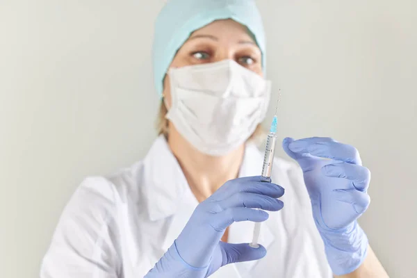 Doctor in the mask holds a syringe with a vaccine against the virus