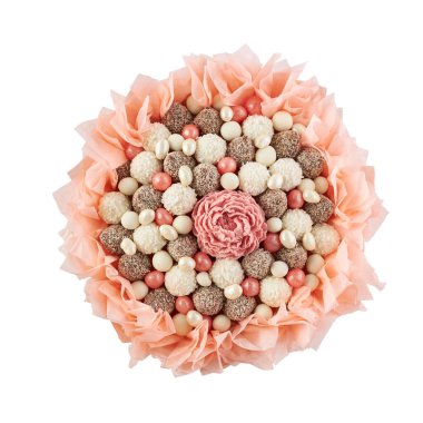 Şeftali rengi kağıda çerçevelenmiş beyaz, kahverengi ve pembe şeker buketi, beyaz arka planda üst manzara.