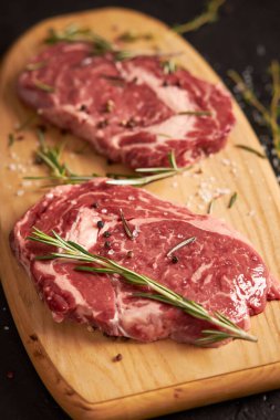 İki sulu pirzola dilimi tahta bir tahtanın üzerinde yatar, dikey görünüm.