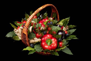 Siyah arka planda çeşitli taze sebzelerle dolu bir sepet.