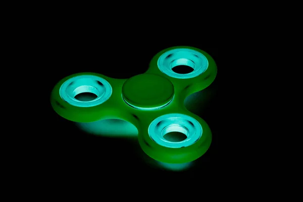 Grüner Fidget Spinner im schwarzen isolierten Hintergrund für Stressabbau während der Arbeit — Stockfoto