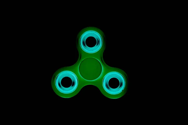 Groene Fidget Spinner in zwarte geïsoleerde achtergrond voor stress release tijdens werk — Stockfoto