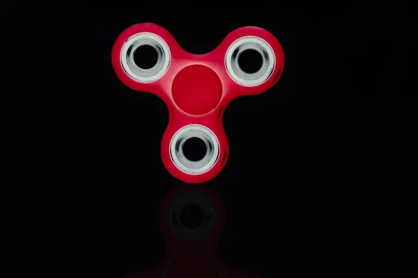 Red Fidget Spinner в черном изолированном фоне для снятия стресса во время работы — стоковое фото