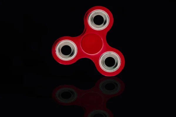 Roter Fidget Spinner in schwarzem, isoliertem Hintergrund für Stressabbau während der Arbeit — Stockfoto