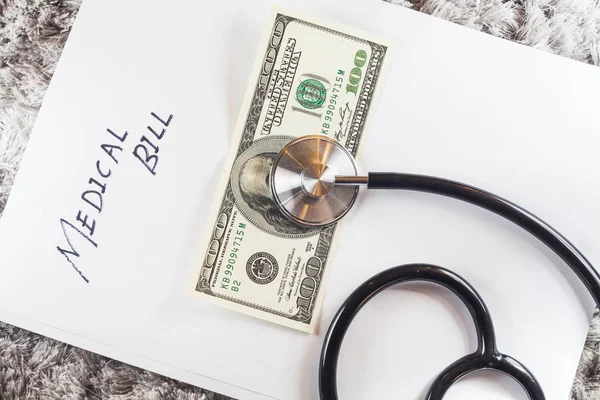 Estetoscopio con la redacción de "factura médica" que muestra una atención médica cara o una factura médica cara con dólares estadounidenses —  Fotos de Stock
