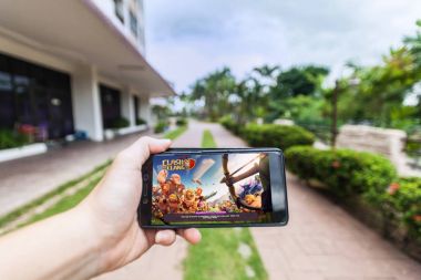 SuperCell'ın çatışma klan oynarken bir cep telefonu tutan el